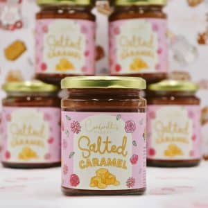 A collection of homemade jars filled with rich, golden salted caramel sauce, topped with simple lids, perfect for gifting or adding a sweet, buttery touch to desserts.