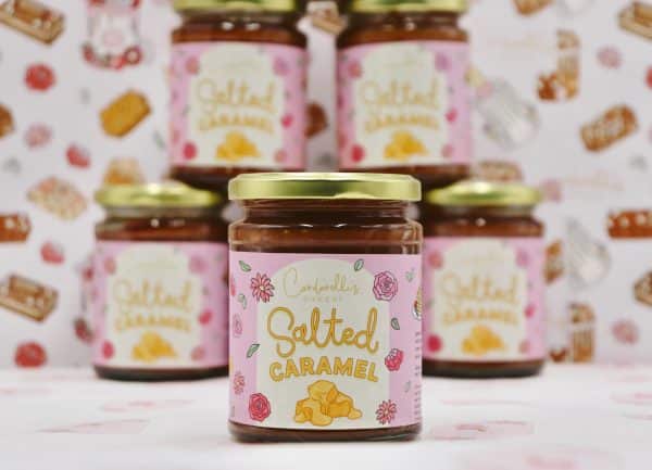 A collection of homemade jars filled with rich, golden salted caramel sauce, topped with simple lids, perfect for gifting or adding a sweet, buttery touch to desserts.